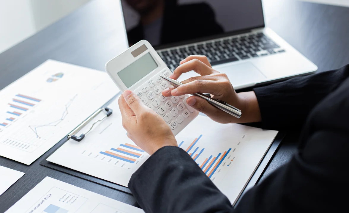 A professional using a calculator with financial charts and reports, representing Geosecure's fuel tax credit optimisation solutions.